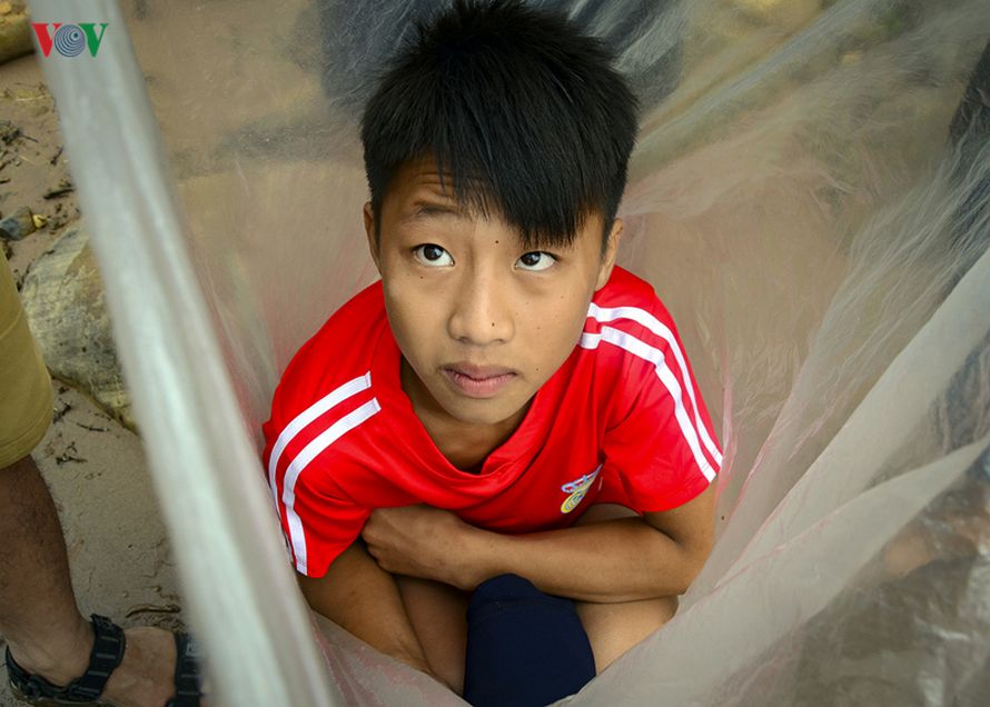 Des enfants dans un village au Vietnam traversent la rivière dans des sacs en plastique pour aller à l’école
