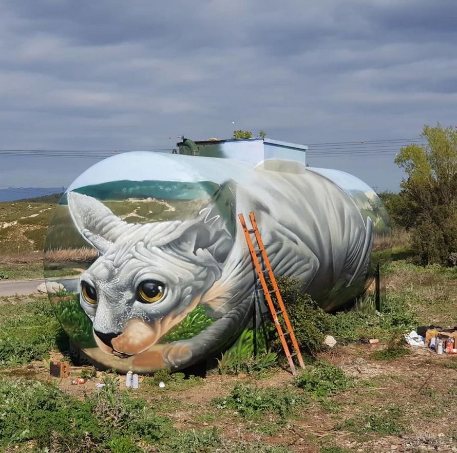 Un artiste de rue peint une illusion bluffante d’un chat sphynx sur un vieux réservoir d’essence