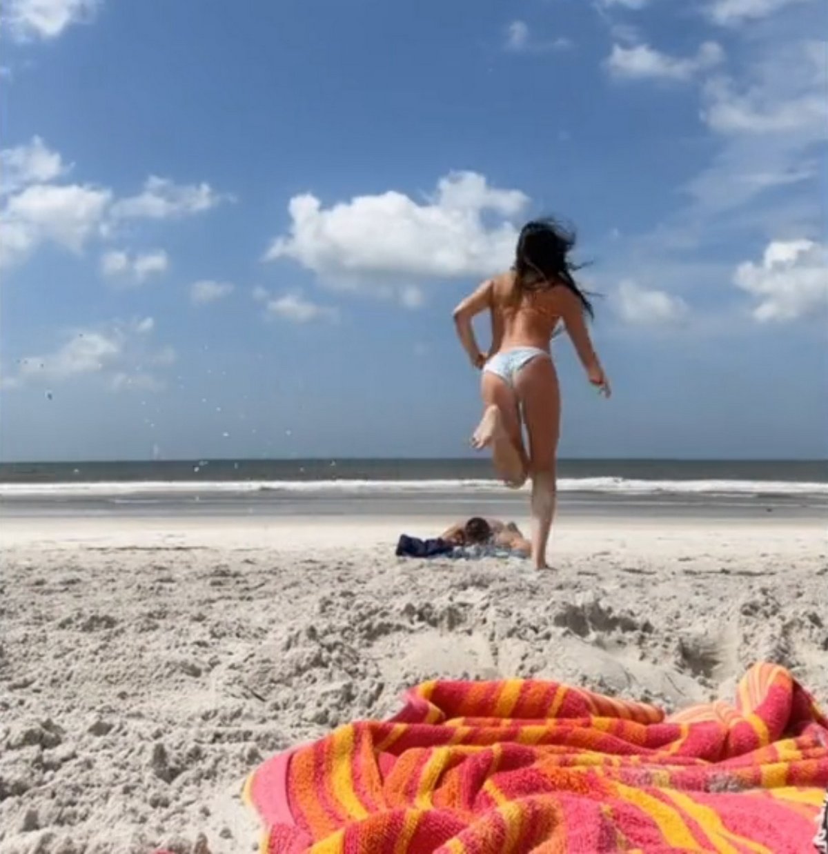 Une femme jette du sable au visage d’un homme après l’avoir vu assis à 3 mètres sur une plage vide