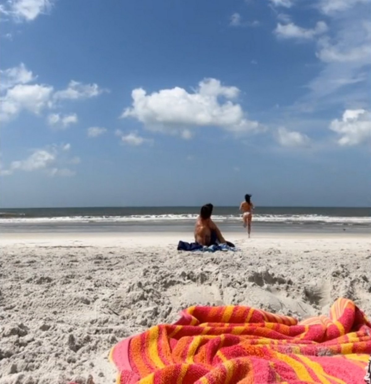 Une femme jette du sable au visage d’un homme après l’avoir vu assis à 3 mètres sur une plage vide